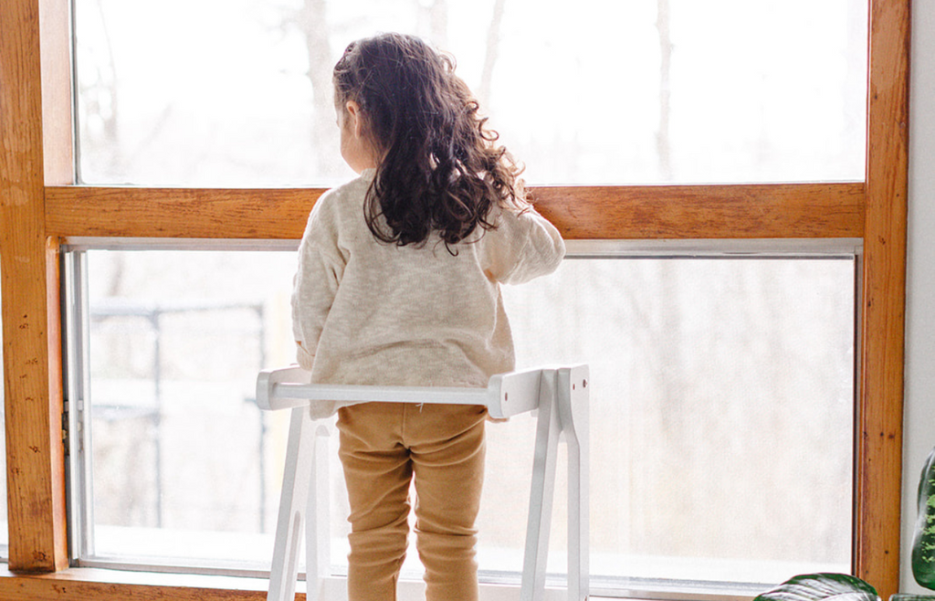 a child looking at the window from her learning tower