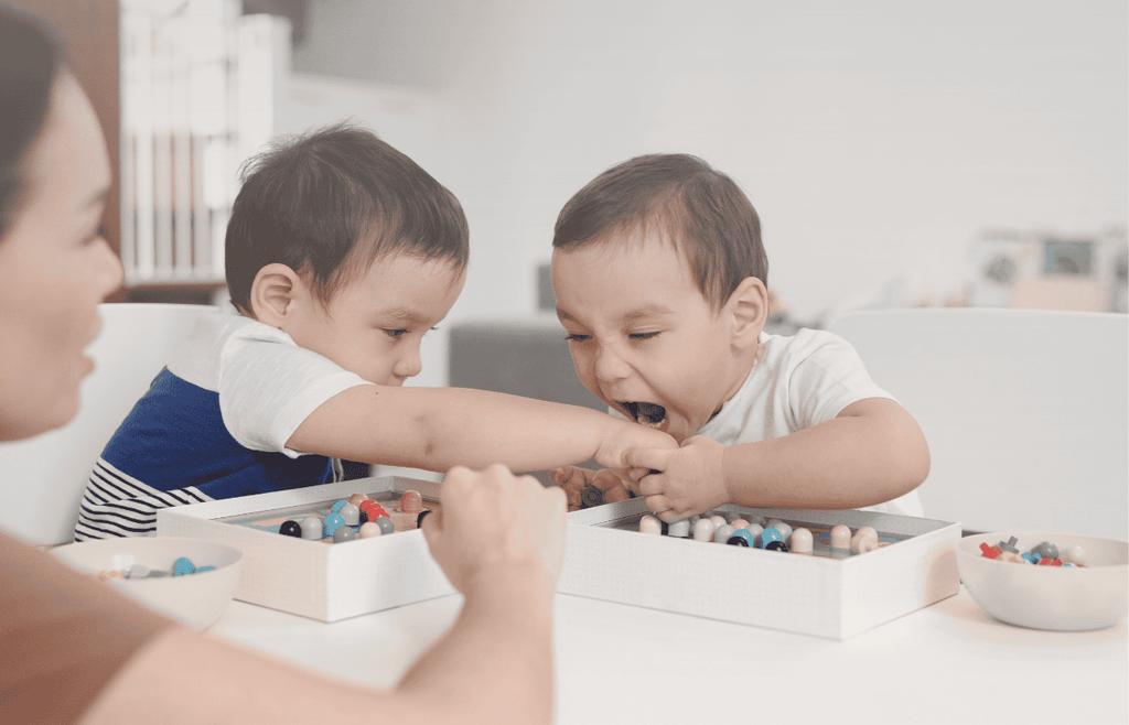 toddler is going to bite the other child's hand