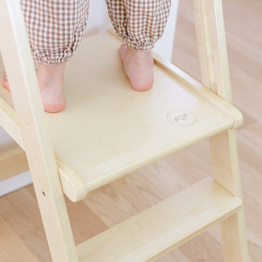 A girls standing in her learning tower with a close up feature the anti slip strips on the tower platforms. 