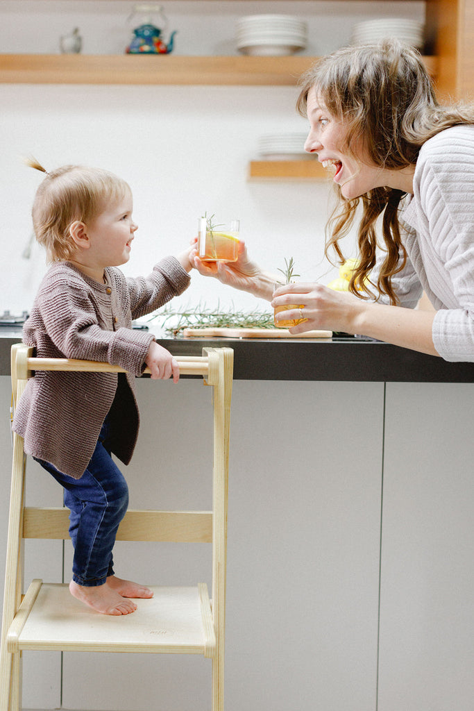 An excited mom sharing cheers with her daughter while standing in a learning tower. 