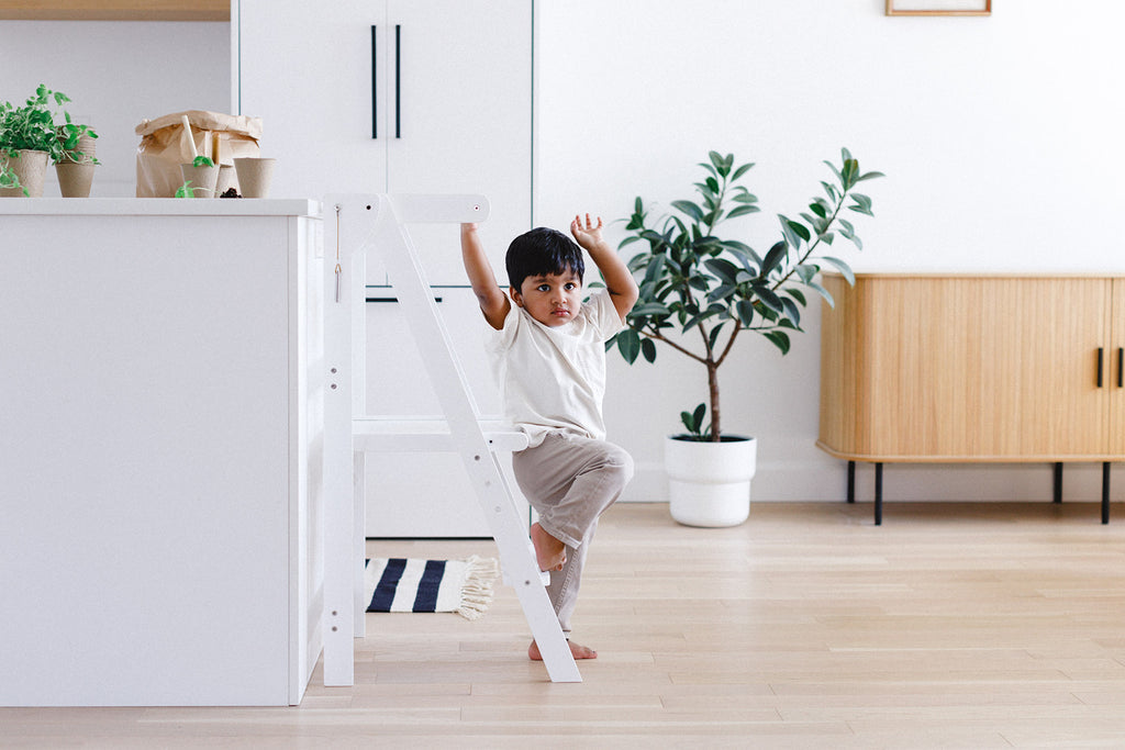  A boy climbing out of his white learning tower independently. 