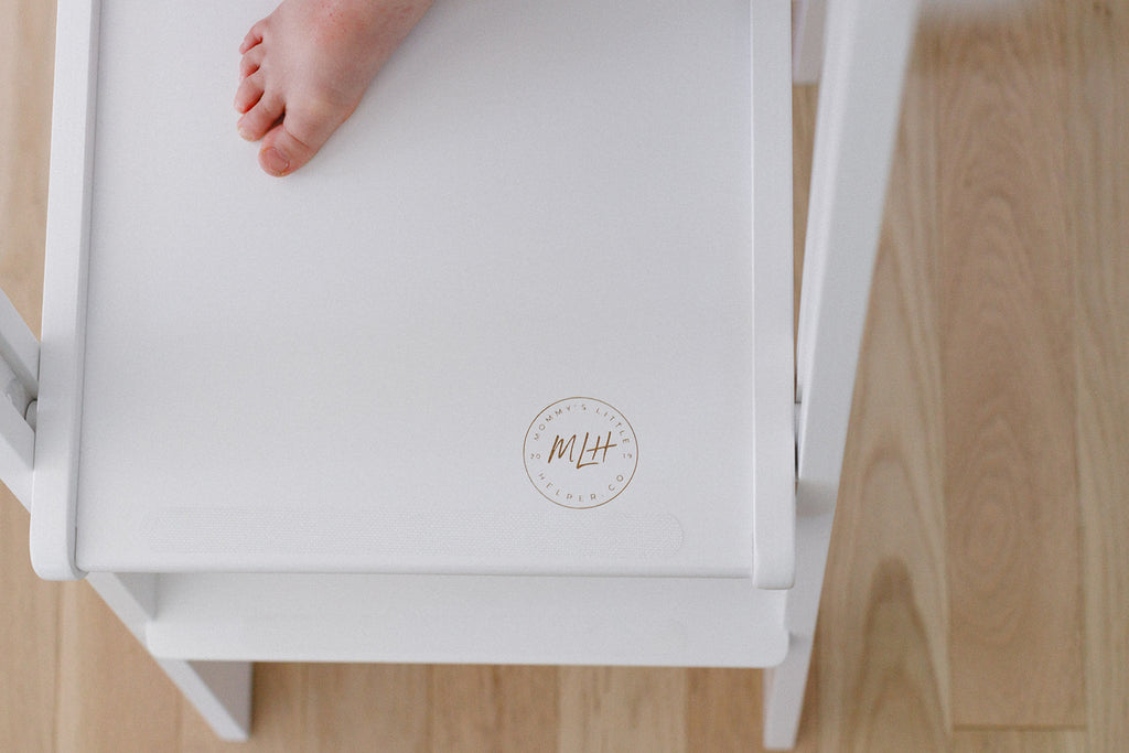 A close up of some toes on a white learning tower with the anti slip strips on the platform. 