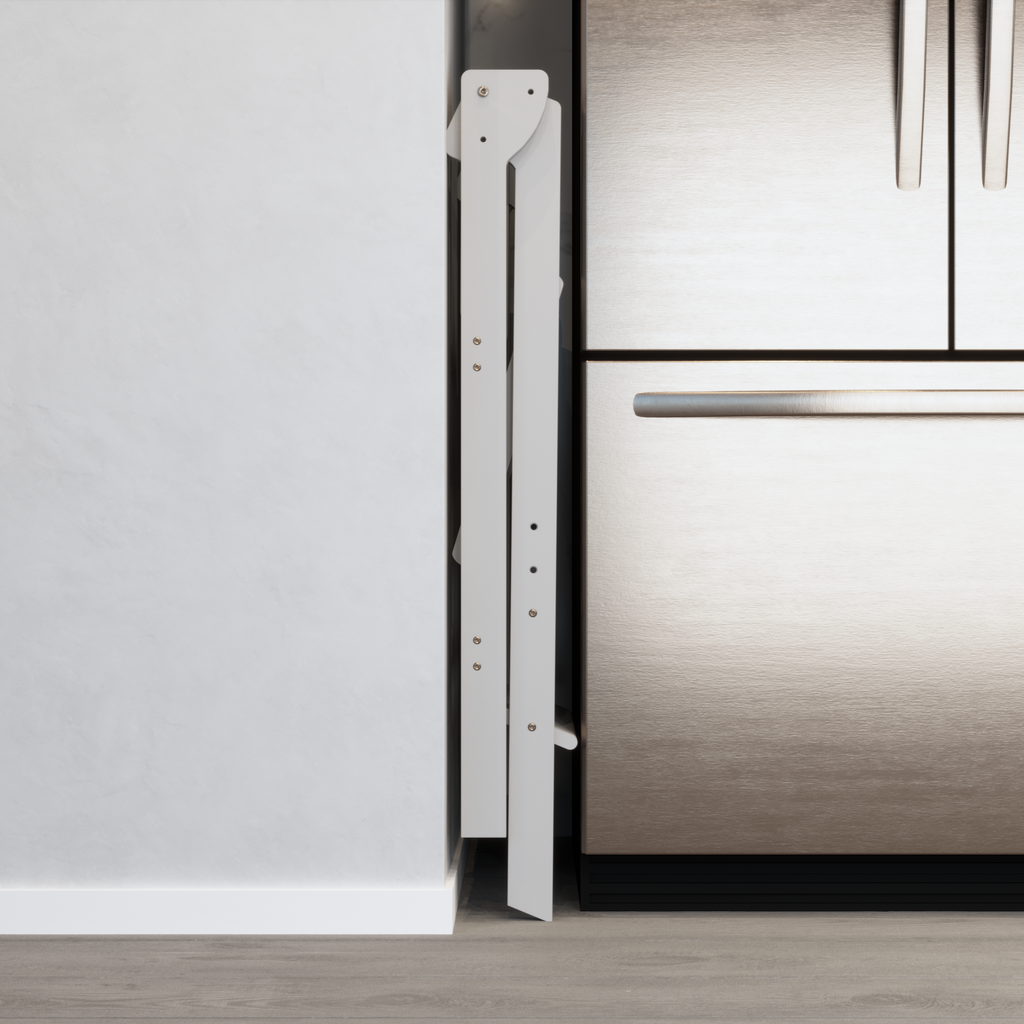 A white kitchen helper tower for toddlers that is folded in a 6 inch gap between a fridge and wall in a smaller kitchen. 