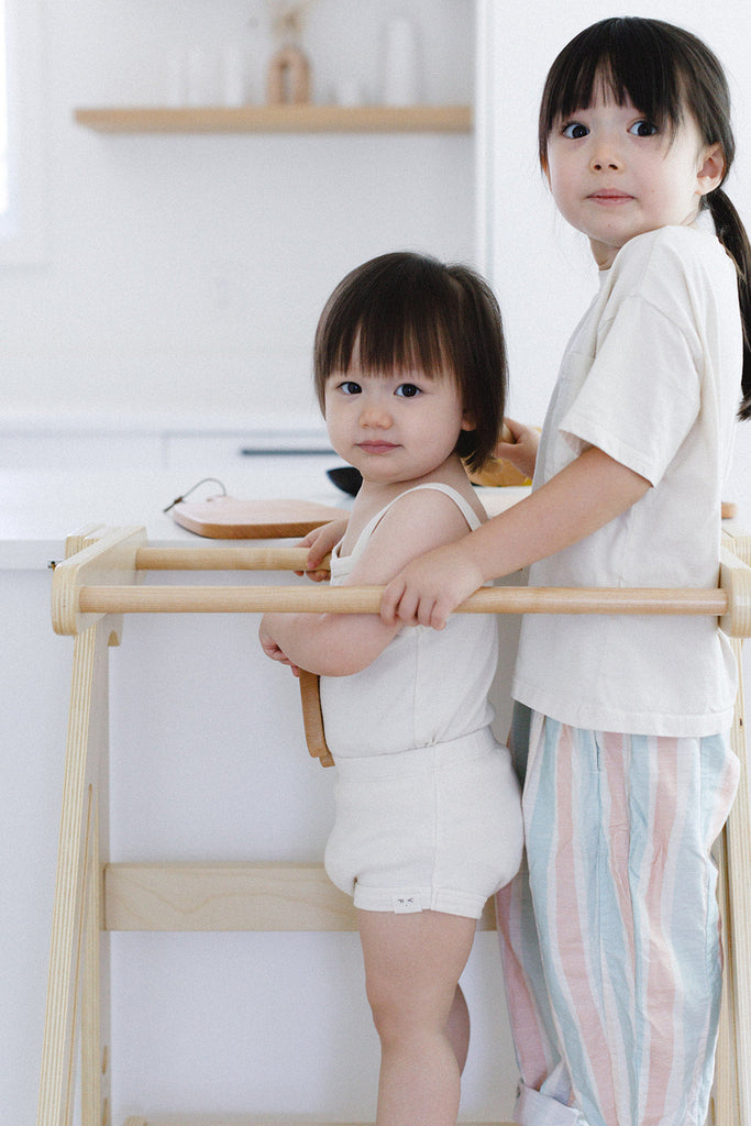 A pair of sisters smiling and looking out of their double wide learning tower