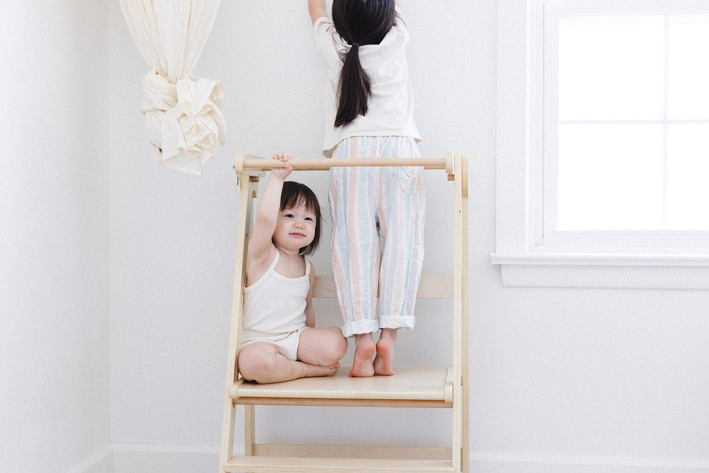 A set of sisters playing in the double wide learning tower. 