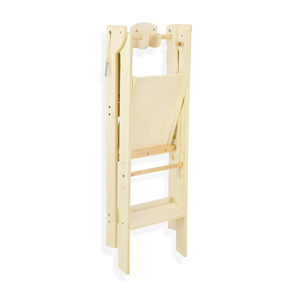 The wooden folding learning tower folded and compactly hanging on the Hook N' Store wall mount