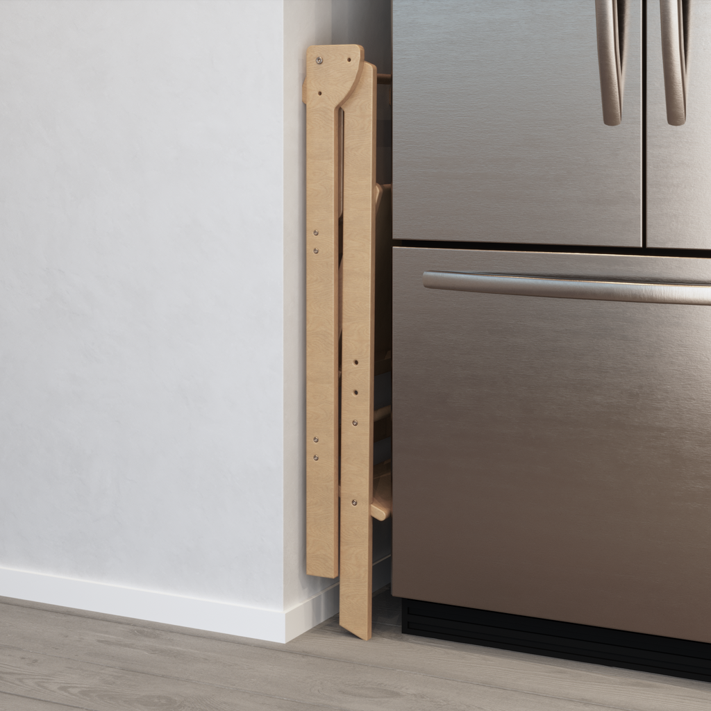A double wide learning tower that is tucked away for storage in the 6 inch gap between a fridge and wall, shown on an angle. 