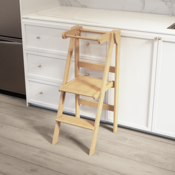 Our new height adjustable folding learning tower up against a white airy kitchen counter. 