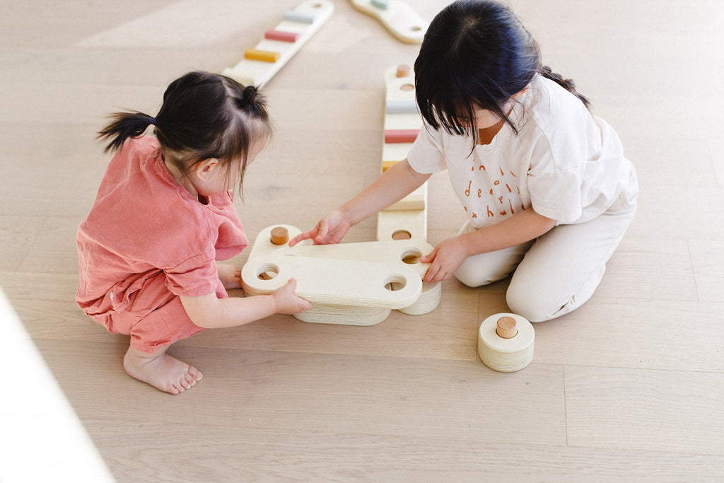 two little girls are trying to assemble the balance beam