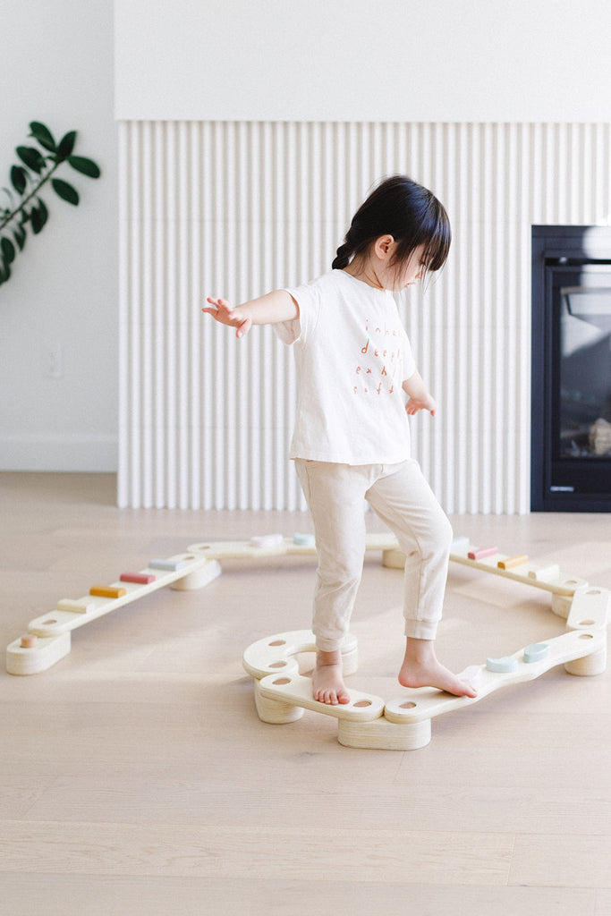 a little girl trying to balance on the beam