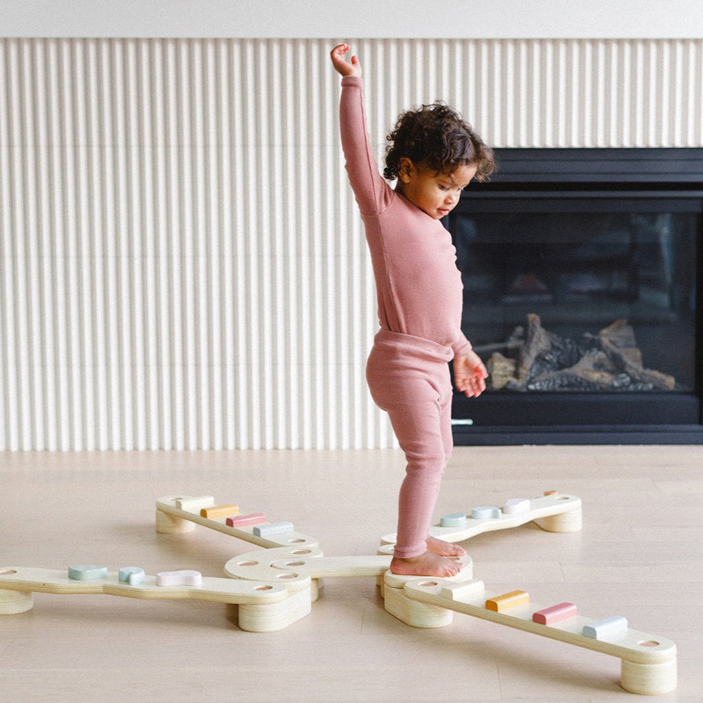 a little girl is trying to balance on the beam
