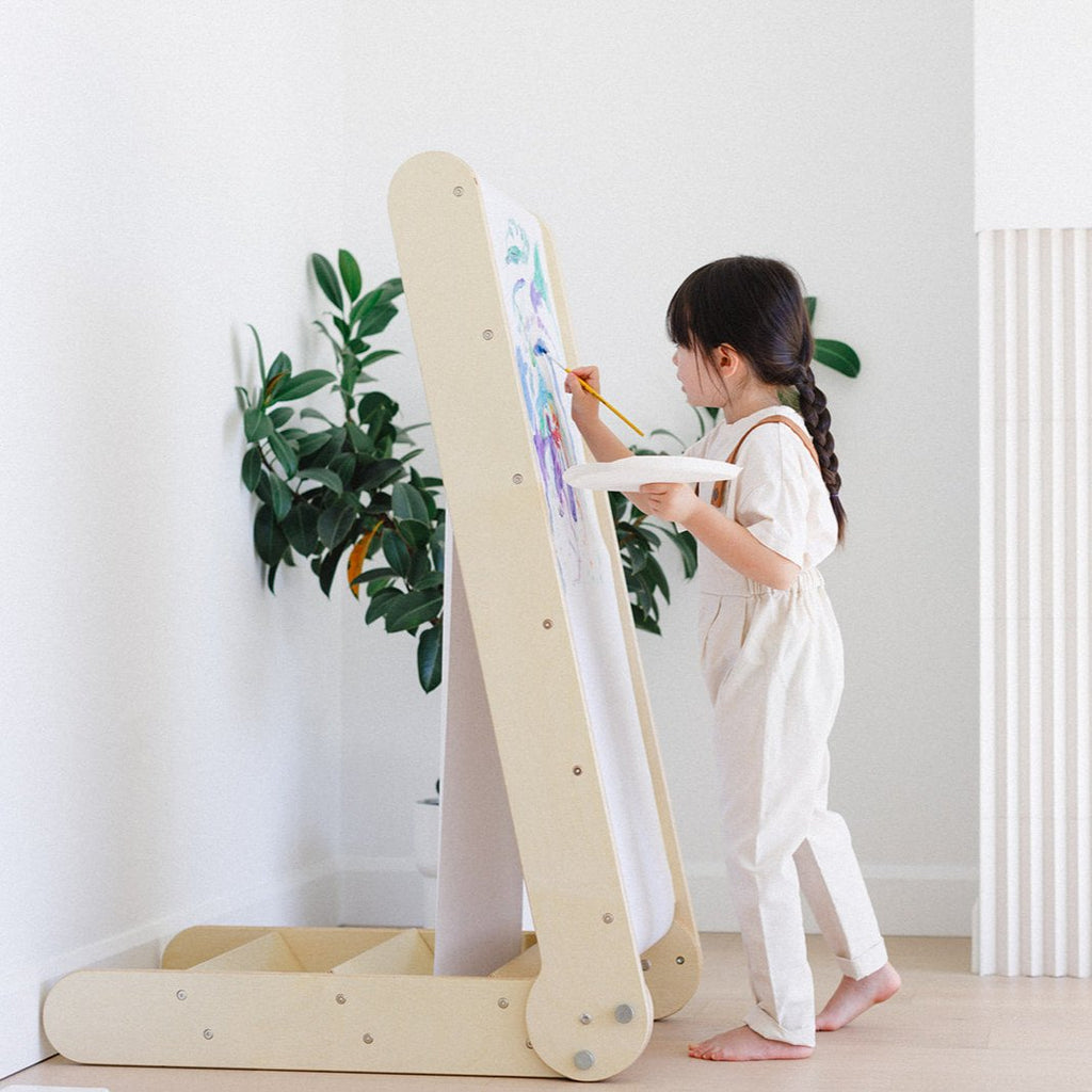 a little girl painting on the slide easel