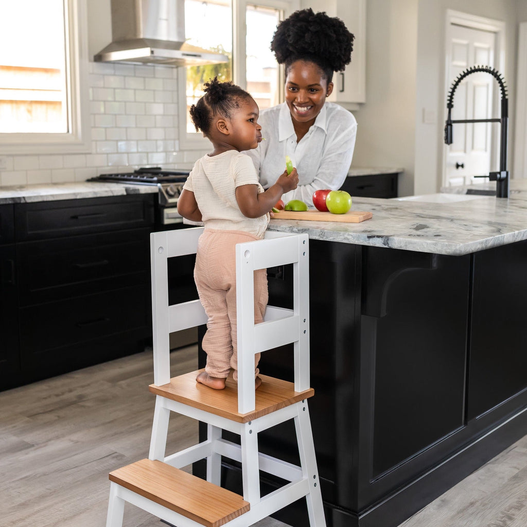 Woman and child in a kitchen with a marble island and black cabinets.