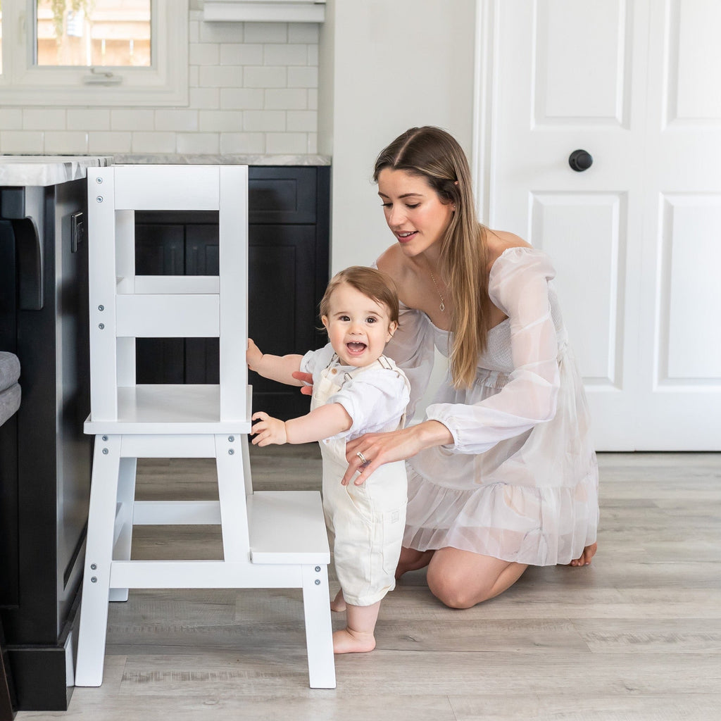 Woman and child in a kitchen with a white step stool.