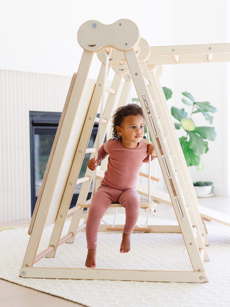 the little girl is swinging in the indoor play gym