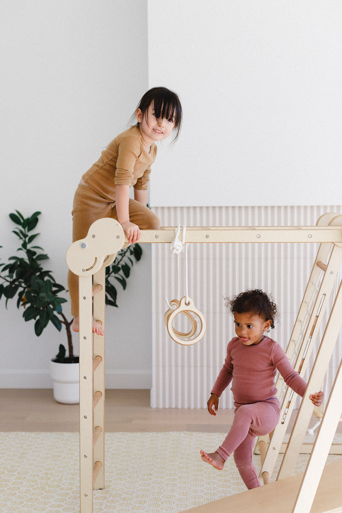 a little girl climbing on the play gym