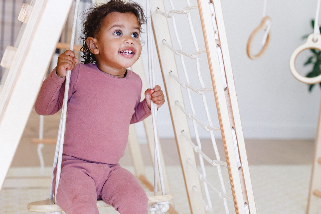 a little girl is smiling while enjoying on the swing