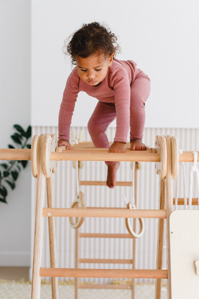 the little girl is at the top of the monkey bars