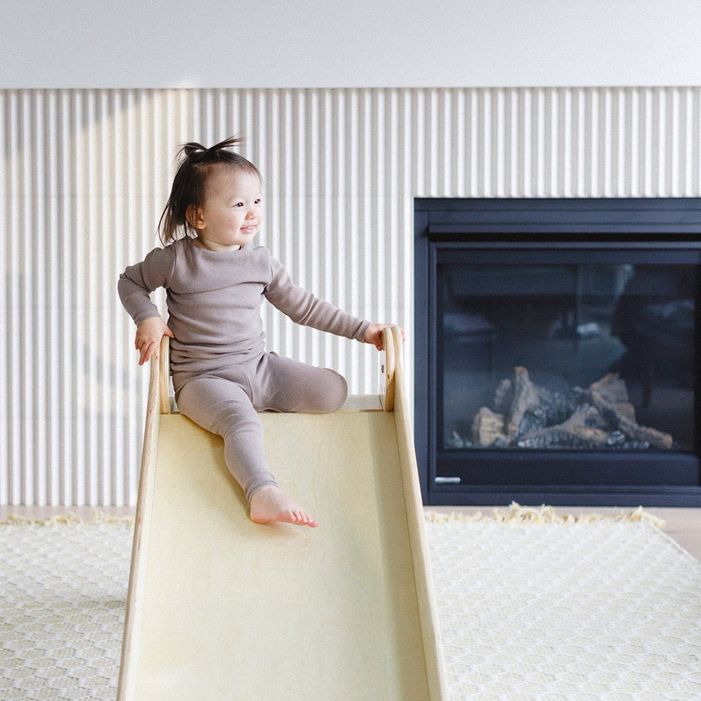 a little girl is posing and smiling at the top of the slide