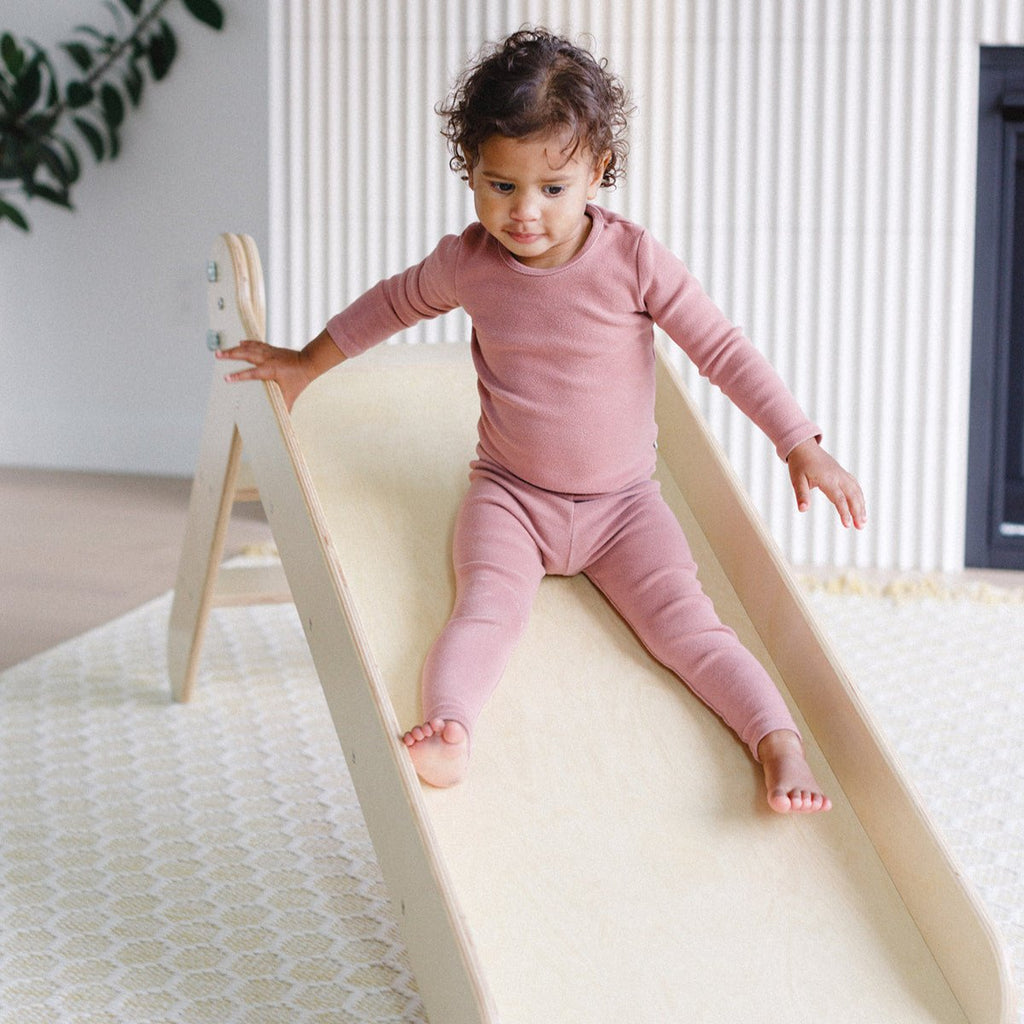 a little girl sliding in the wooden slide