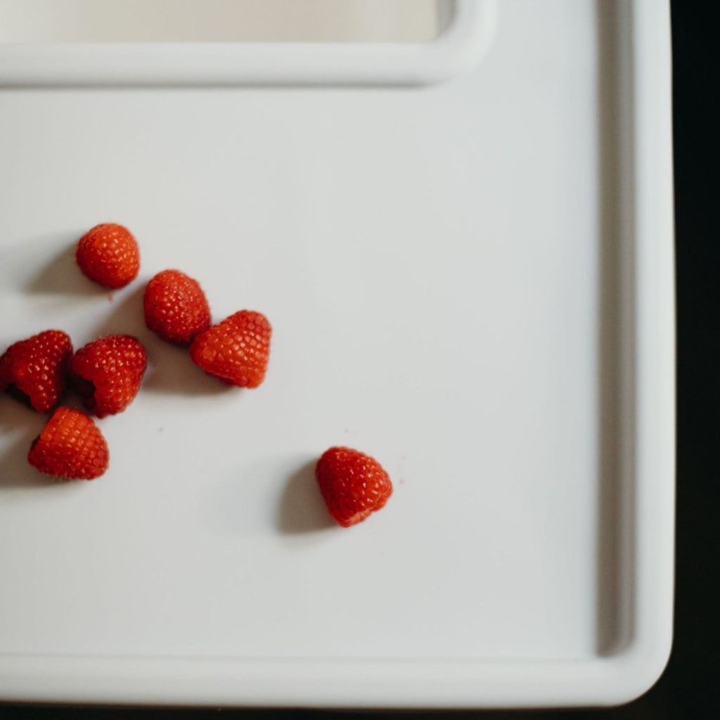 Overhead view of raspberries on the Ikea Antilop Highchair Full Coverage Placemat Cover in Mellow Grey style