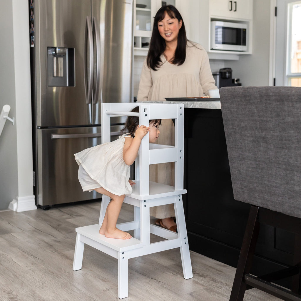 White and Walnut color Classic Montessori Toddler Learning Tower against a kitchen counter - child entering tower safely
