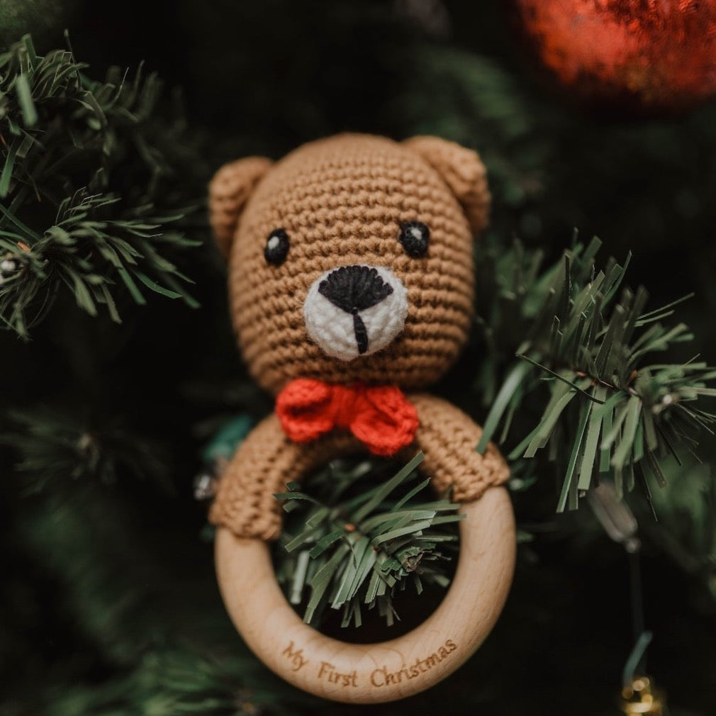 Bear style baby's first christmas crochet rattle with wooden handle being used as a christmas tree ornament