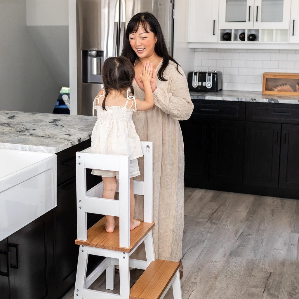 Toddler giving mom two high-five's using Montessori Toddler Learning Tower Kitchen Helper
