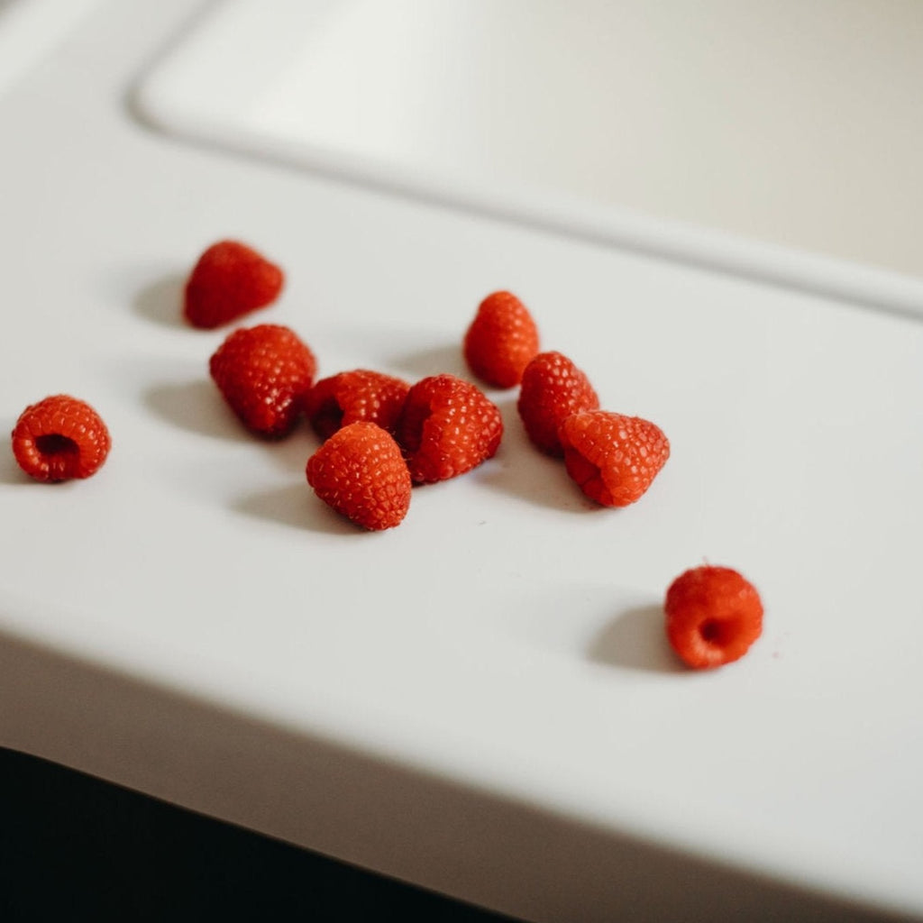 Overhead view of raspberries on the Ikea Antilop Highchair Full Coverage Placemat Cover in Mellow Grey style