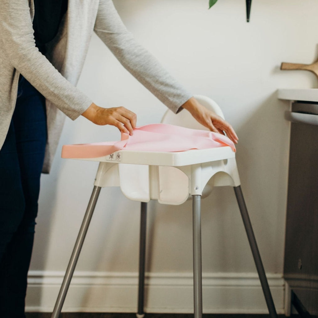 IKEA Antilop HighChair Full Coverage Placemat Cover in Rosy Pink style on a white highchair being easily removed for cleaning
