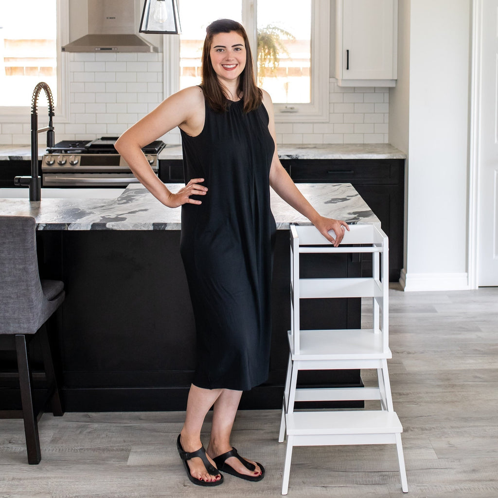 Rachel, owner of MLHCo, posing with White Classic Montessori Toddler Learning Tower Kitchen Helper