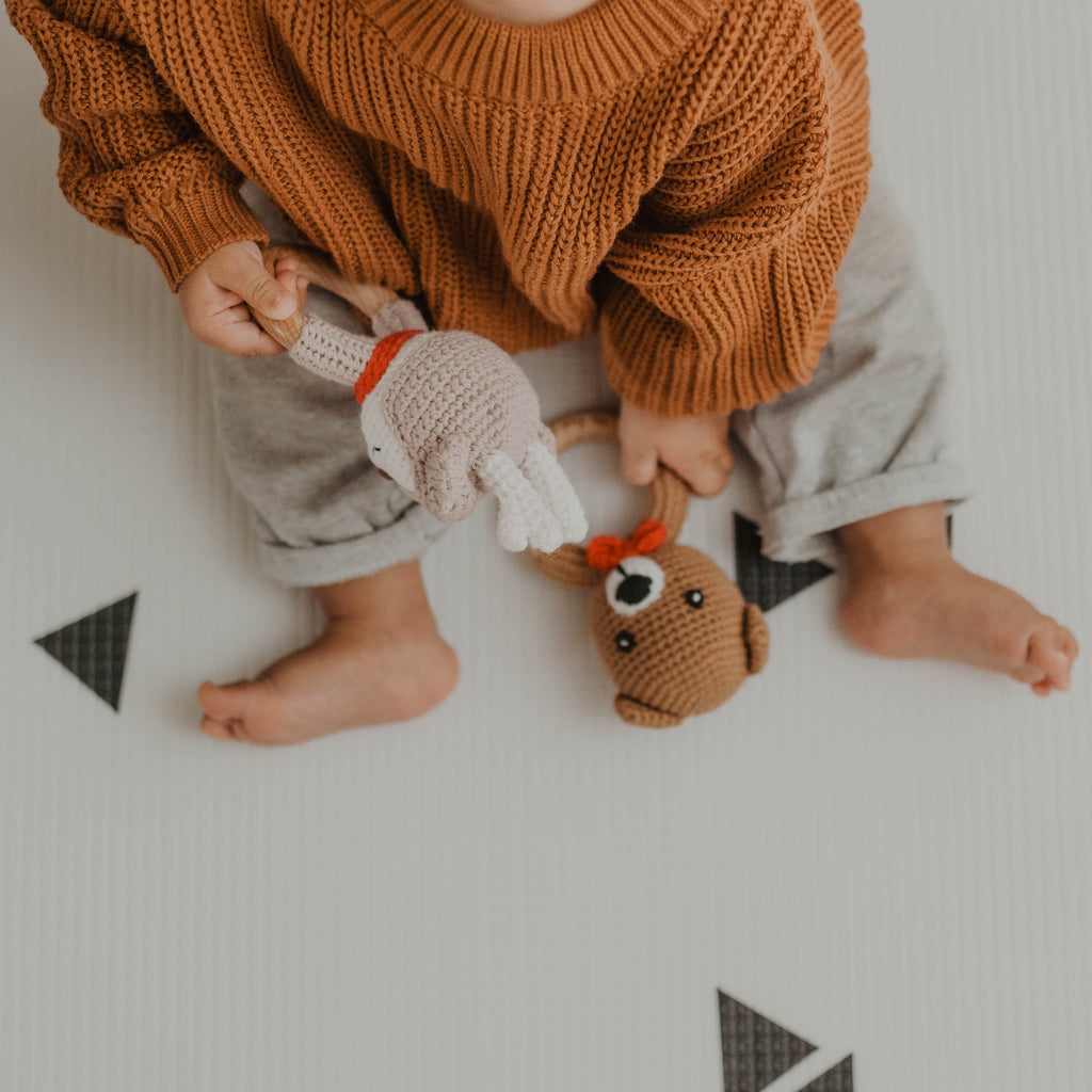 Overhead view of child holding fawn and bear crochet baby 's first christmas wooden handle rattle