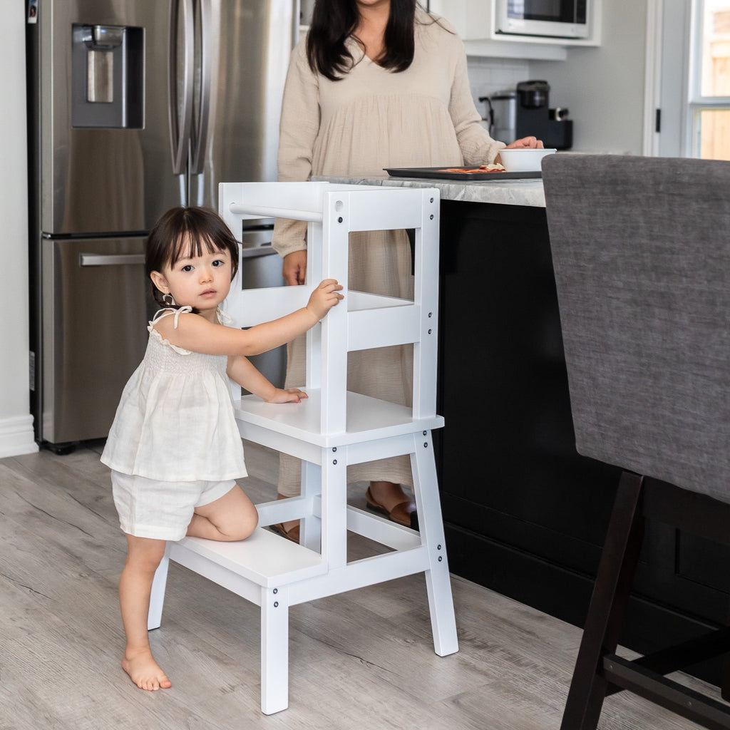White and Walnut color Classic Montessori Toddler Learning Tower against a kitchen counter - child entering tower safely