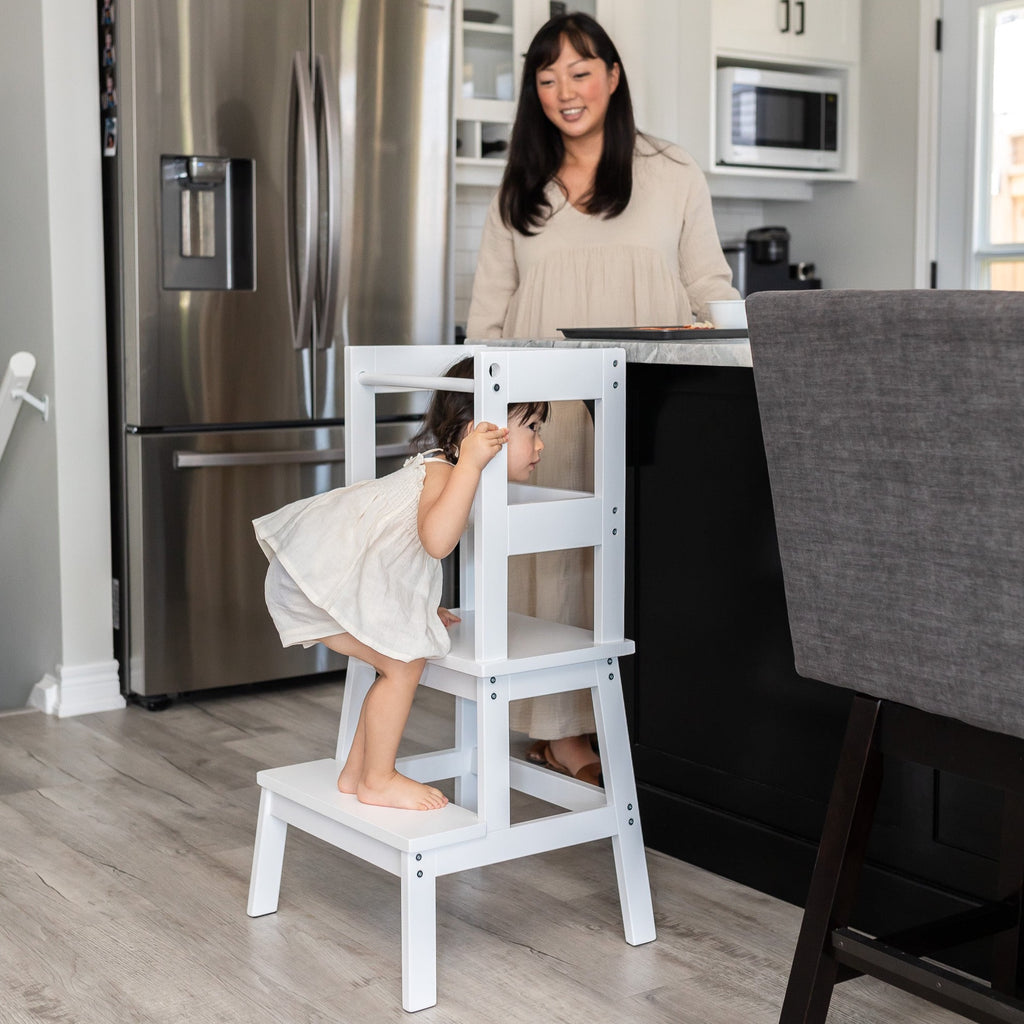 Clean White Enamel color Classic Montessori Toddler Learning Tower against a kitchen counter - child entering tower safely